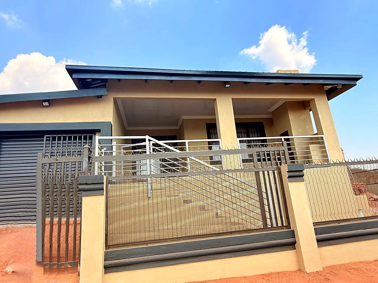 Completed home with butterfly roof, garage, covered patio, balustrades, gates and boundary wall