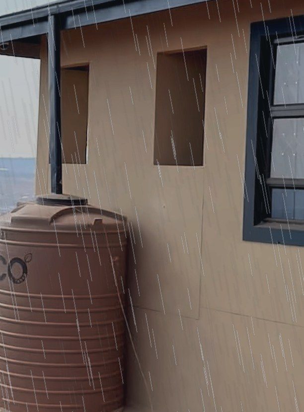 Downpipe feeding a rainwater tank in the rain