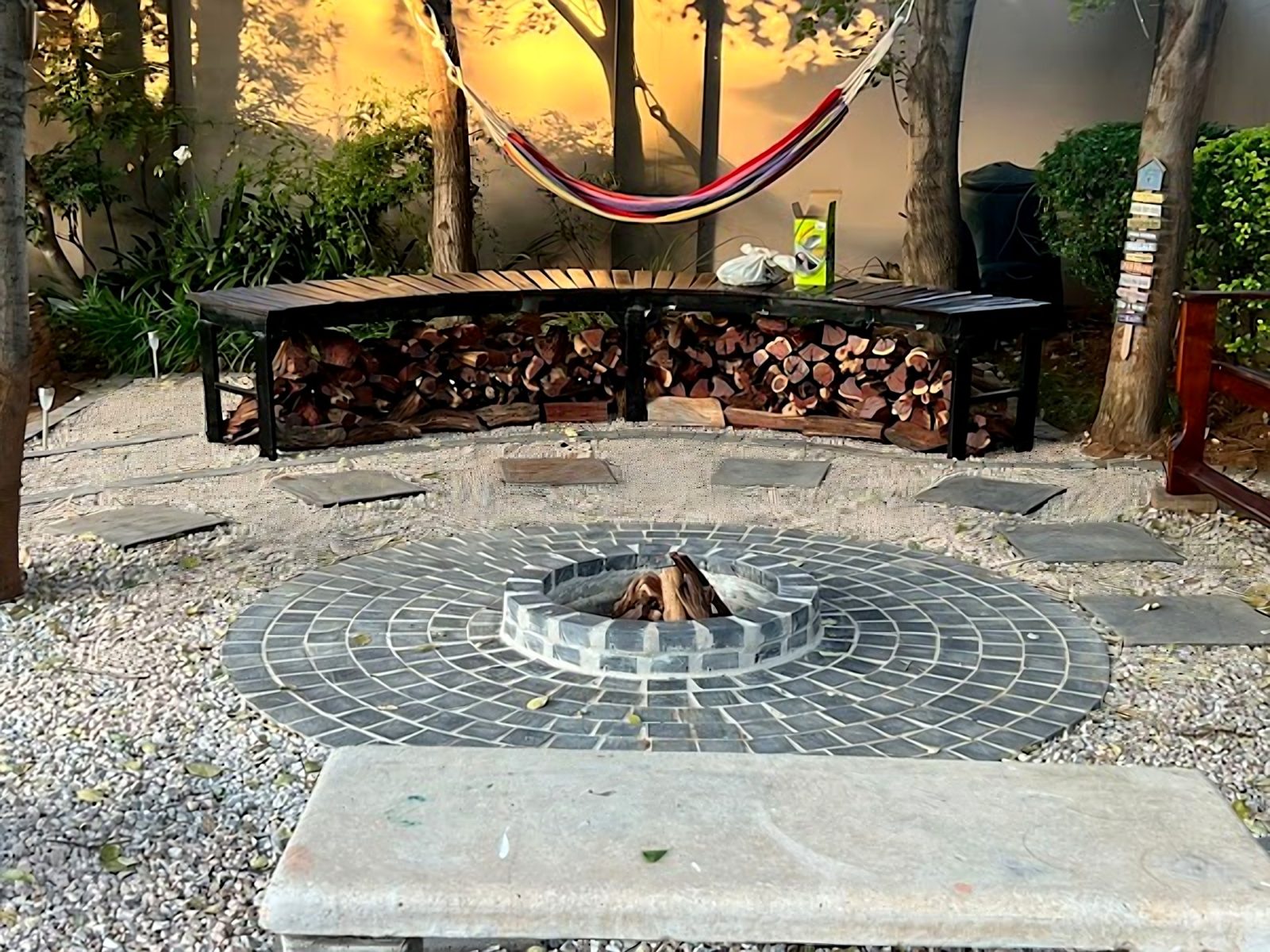Garden after: paved circular fire pit, gravel, stepping stones and curved bench