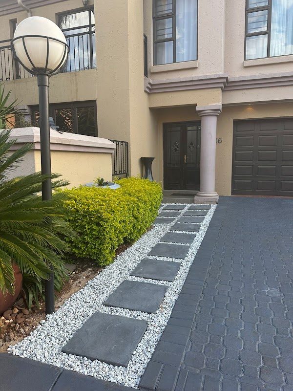 Stepping-stone walkway with white gravel beside paved driveway